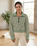 Woman wearing the Eucalyptus Gold half-zip fleece pullover in a sunlit yoga studio
