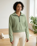 Woman wearing the Breath Lines Sage half-zip fleece pullover in a sunlit yoga studio