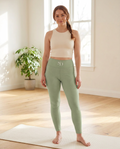 Woman wearing the Breath Lines Sage high-waisted yoga leggings on a yoga mat