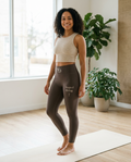 Woman wearing the Rooted & Rising espresso high-waisted yoga leggings with SD waistband on a yoga mat