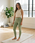 Woman wearing the Breathe. Begin Again. sage high-waisted yoga leggings with SD waistband on a yoga mat